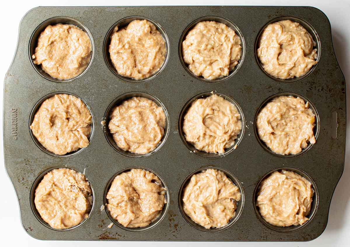 A muffin tin with peanut butter banana batter filled almost to the top.