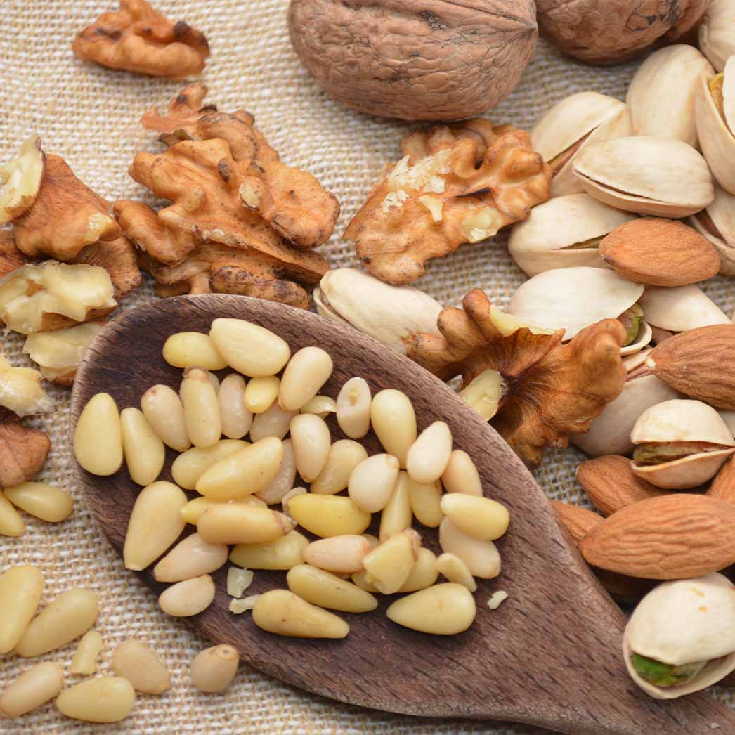 Nuts to use in the nasturtium pesto recipe, including pine nuts, pistachios, almonds, and walnuts.