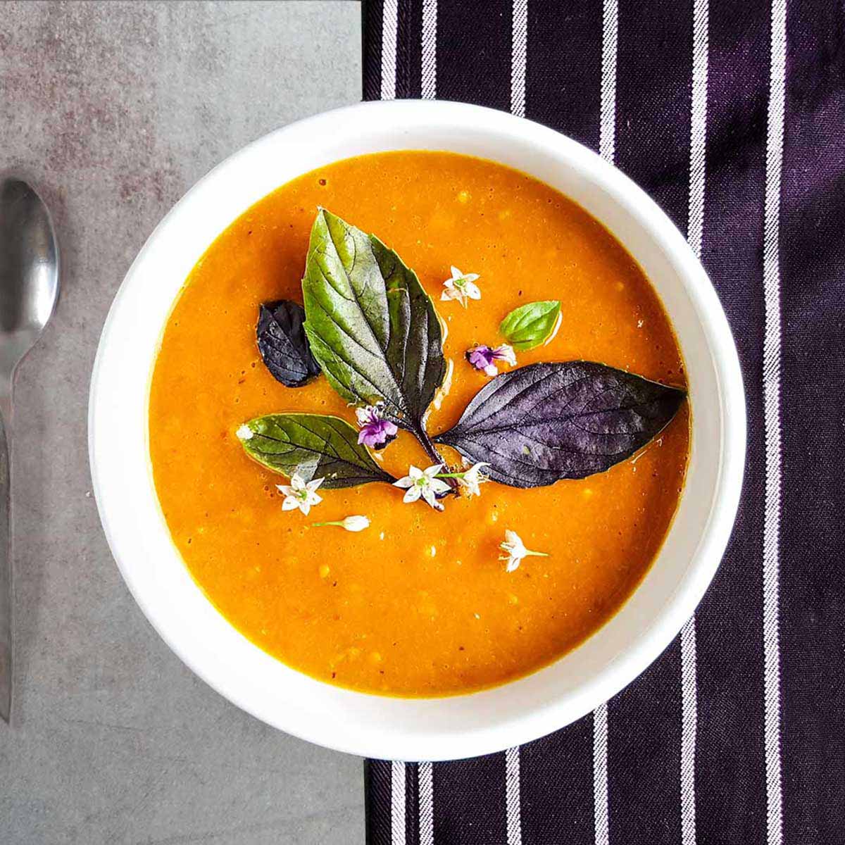 A bowl of roasted tomato soup topped with fresh basil leaves