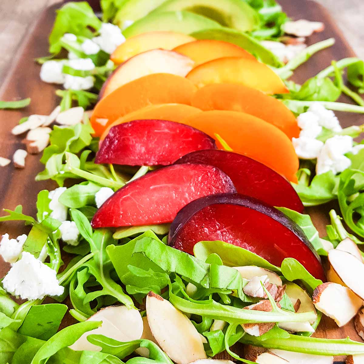 A stone fruit salad with peaches, nectarines, plums, and apricots, along with goat cheese and arugula.