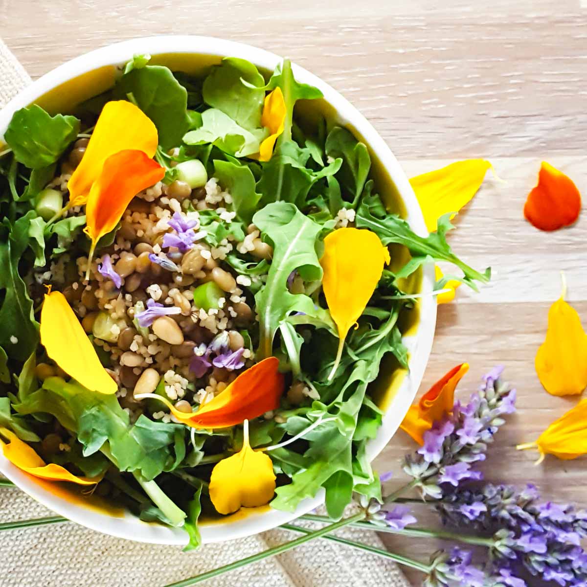 A salad bowl with arugula, lentils, and scattered edible flowers