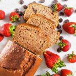 Slices of strawberry chocolate chip bread surrounded by strawberries and chocolate chips