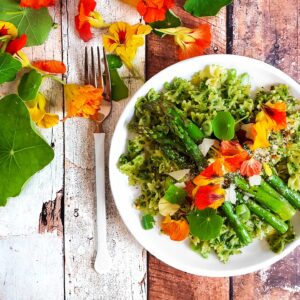 Plate of pasta with asparagus and nasturtium leaves and flowers on the table