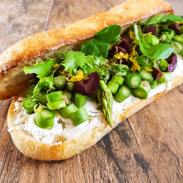 Baguette roll with sliced asapragus, goat cheese, olives, and lettuce