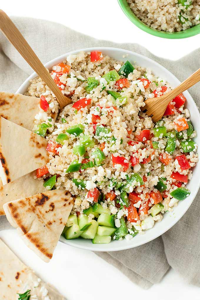 A bowl with quinoa, tomatoes, cucumbers, and bell peppers.