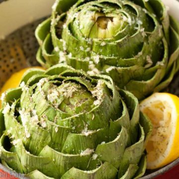 artichokes in a steamer basket with lemons