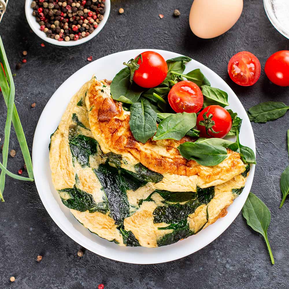 A spinach omelet on a black table top to show that you can replace it with nasturtium