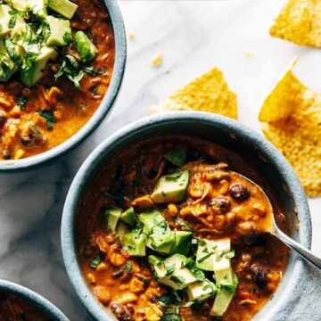 Bowls of queso chicken chili topped with avocado. Recipe by Pinch of Yum.