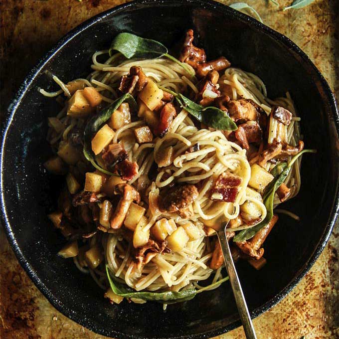 A pan of pasta with apples, bacon, and sage. Recipe by Heather Christo