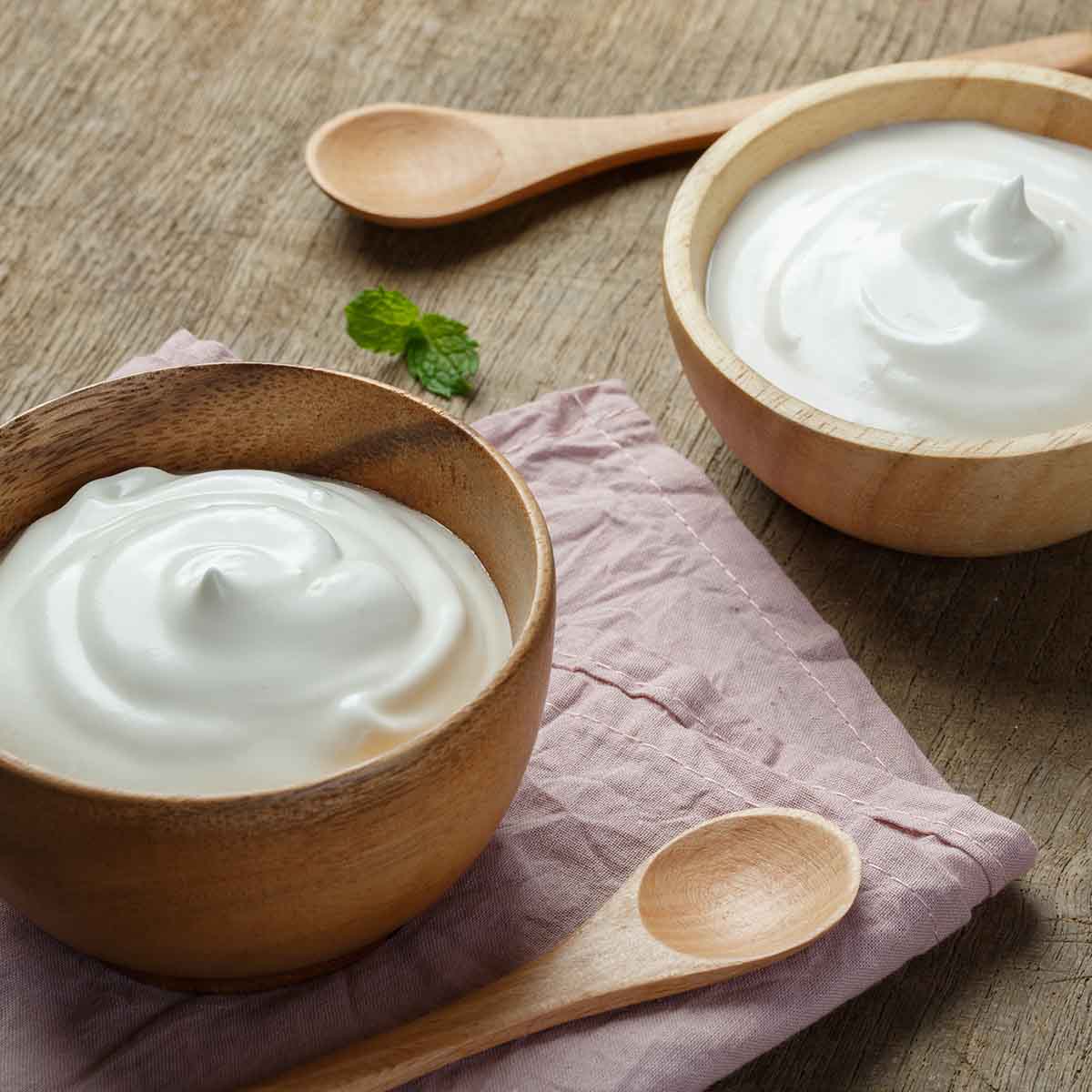 Greek yogurt and alternatives in wooden bowls before making tzatziki