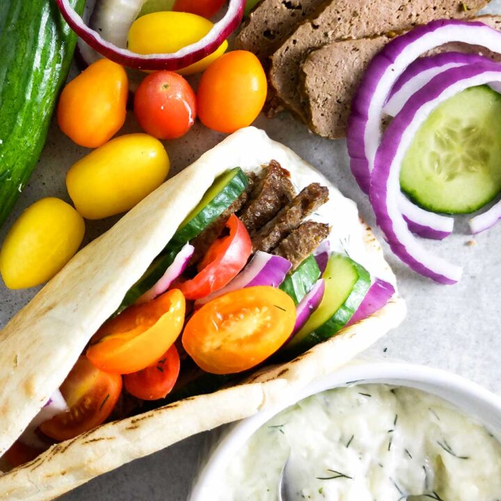 A gyro filled with homemade meat, vegetables, and tzatziki sauce