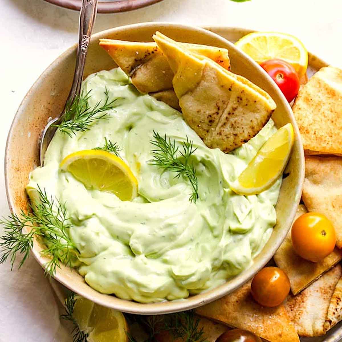 Avocado tzatziki variation with pita bites in a bowl. Recipe from Two Peas & Their Pod
