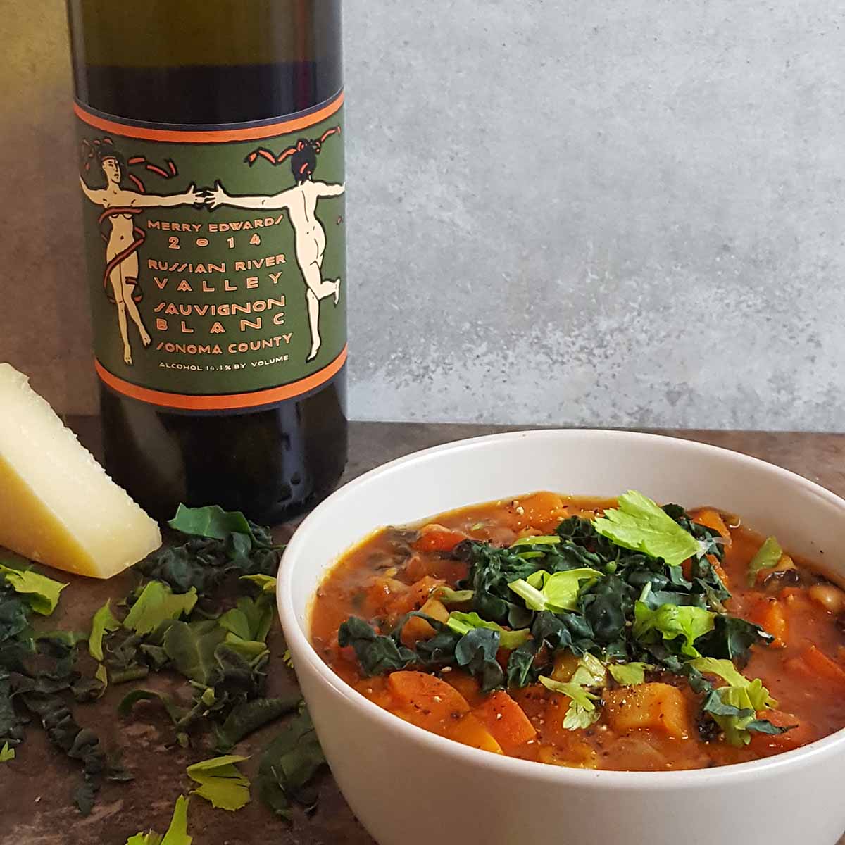 Finishing a winter minestrone soup with white wine before serving.