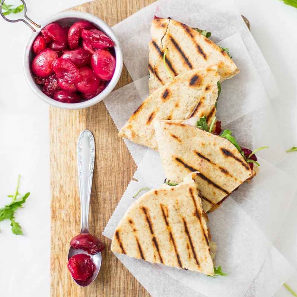 Grilled quesadillas cut into triangles, made with brie, bacon, and roasted cherries. Recipe from Use Your Noodles.