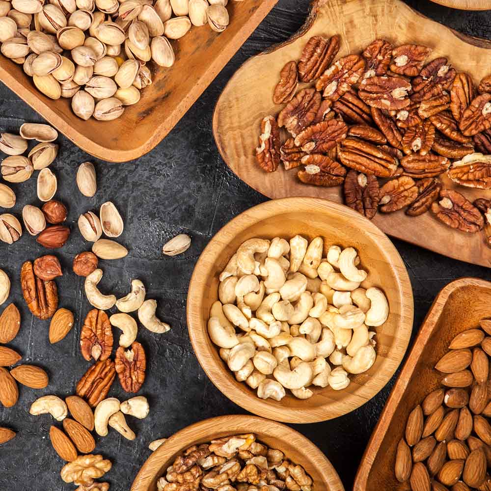Bowls of nuts on a table, including pecans, pistachios, almonds, and cashews. All ready to pair with grapefruit.