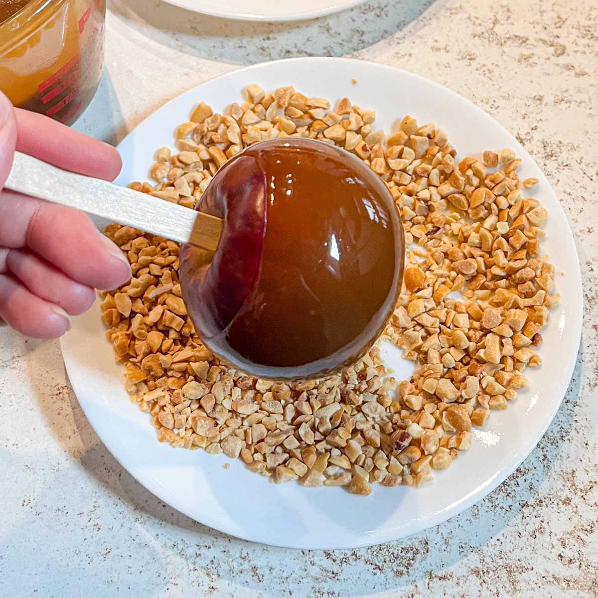 An apple rotated around to help the caramel set before dipping it in toppings.