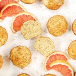 Grapefruit poppy seed muffins on a table with slices of fresh grapefruit