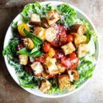 A plate of Caesar salad with tomatoes and homemade croutons.