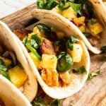 Blackened tilapia fish tacos with pineapple salsa on a wood serving tray