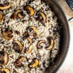 A pan of wild mushroom risotto topped with cremini mushrooms