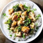 Mandarin orange chicken in a sauce with broccoli, sesame seeds, green onions and rice