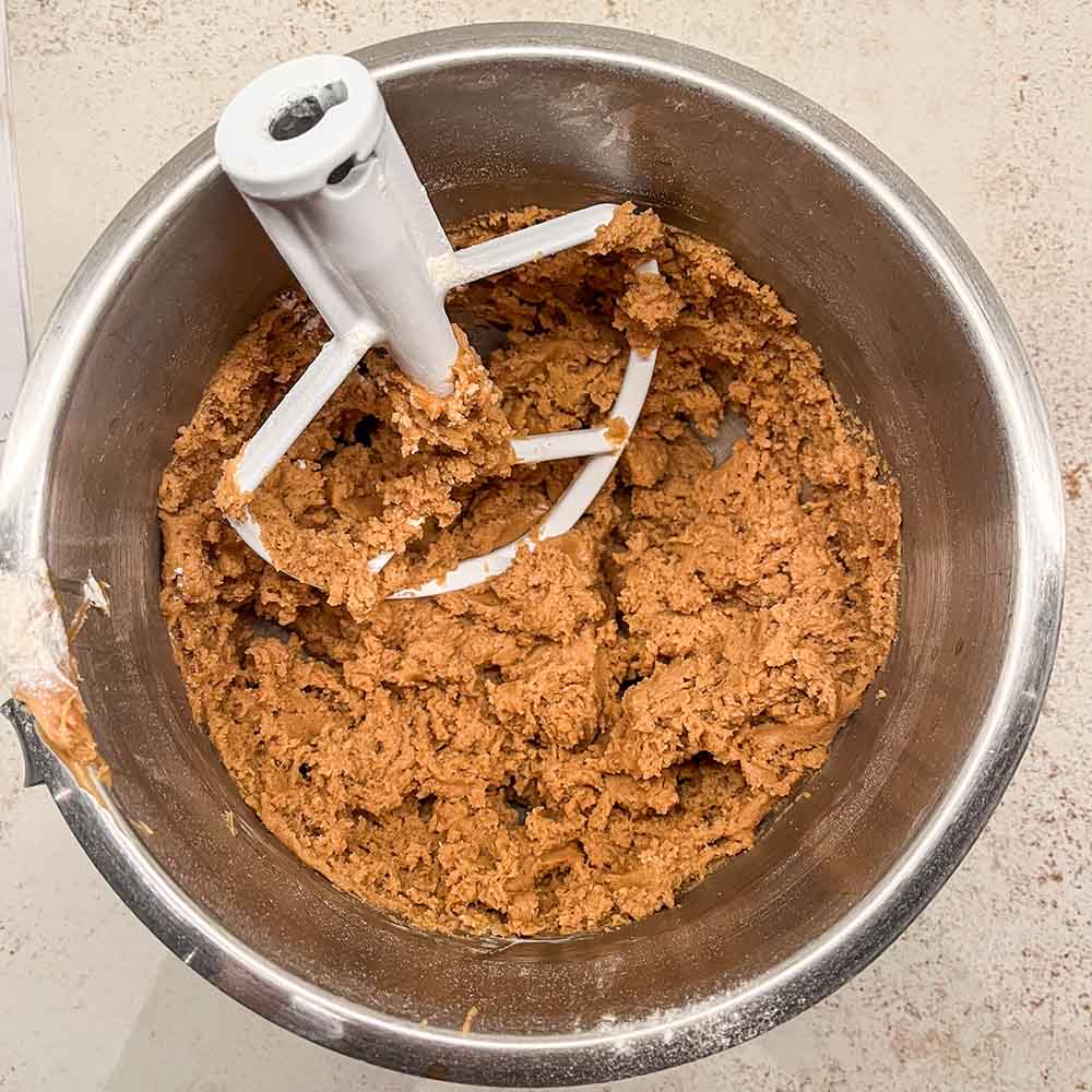 Peanut butter blossom cookie dough in a stand mixer bowl. The recipe uses melted butter, so it can also be easily mixed by hand.