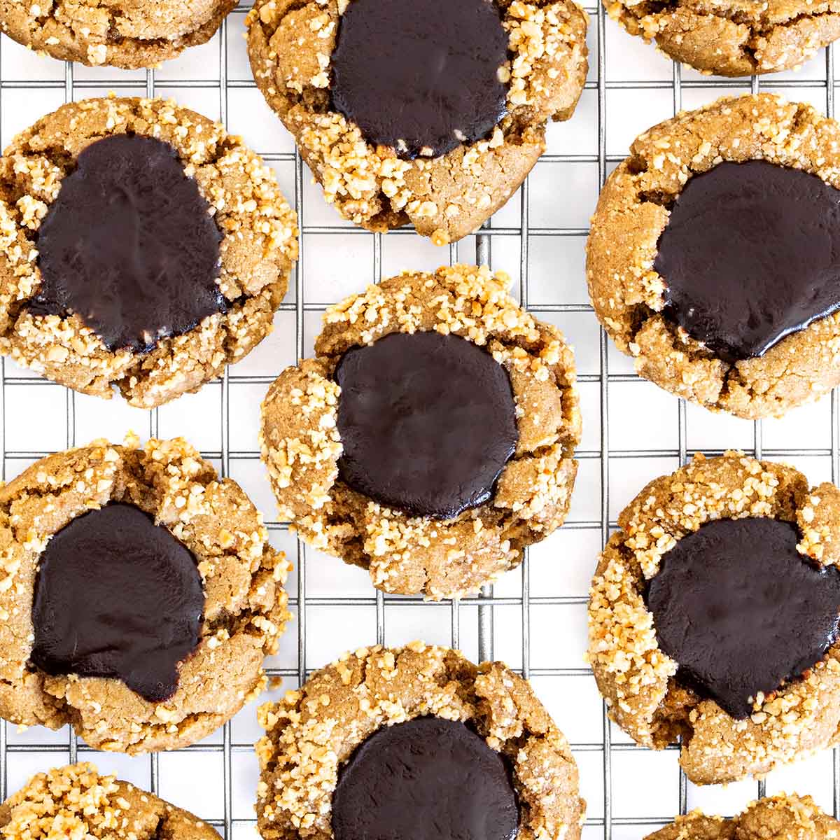 Soft peanut butter blossoms fill with a chocolate center and fresh peanuts, lined up on a cooling rack.