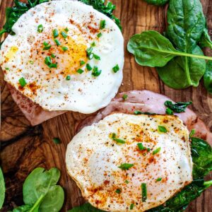 Eggs Benedict Florentine with spinach, on a wood counter