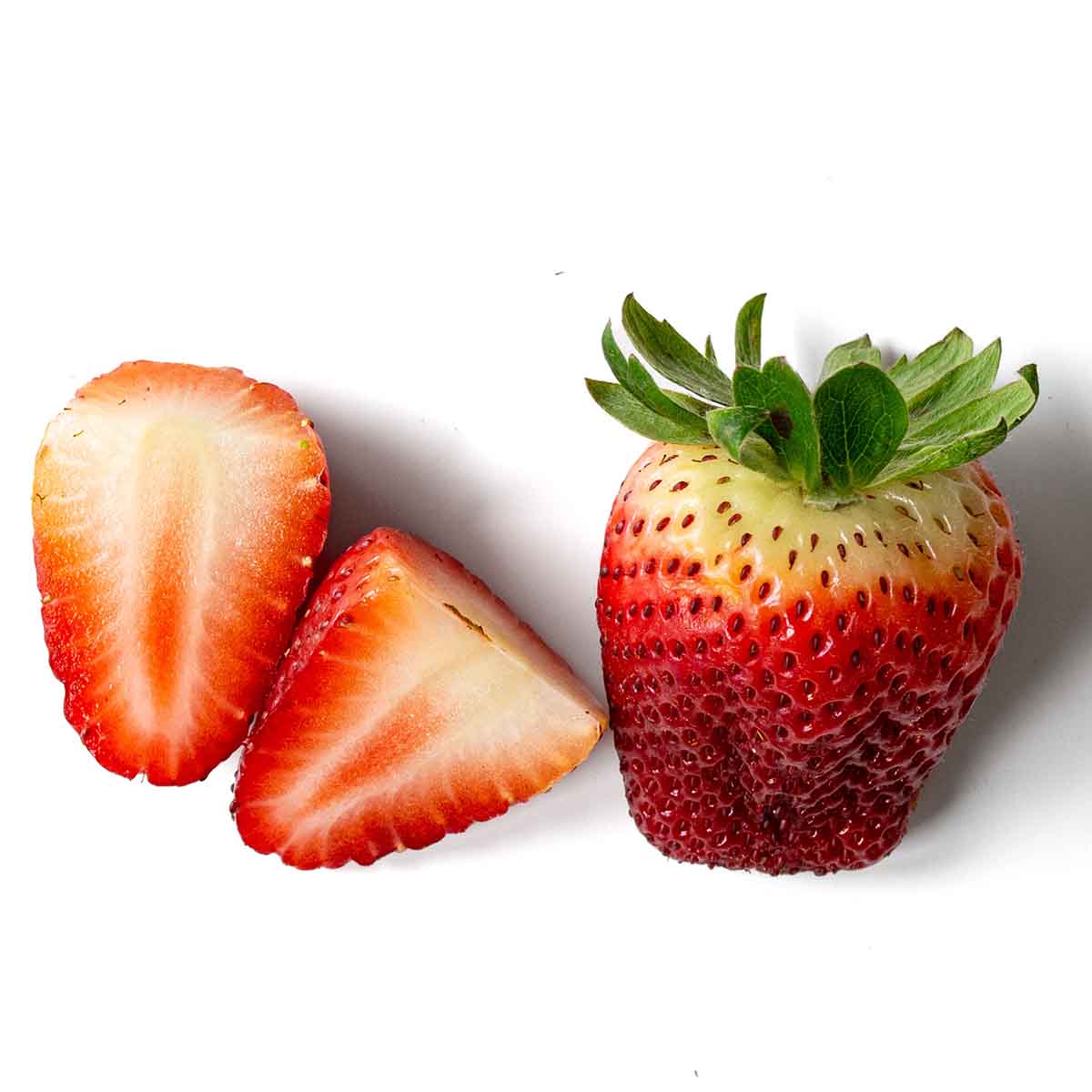 An under-ripe, bland strawberry with white shoulders, cut in half to reveal white center.