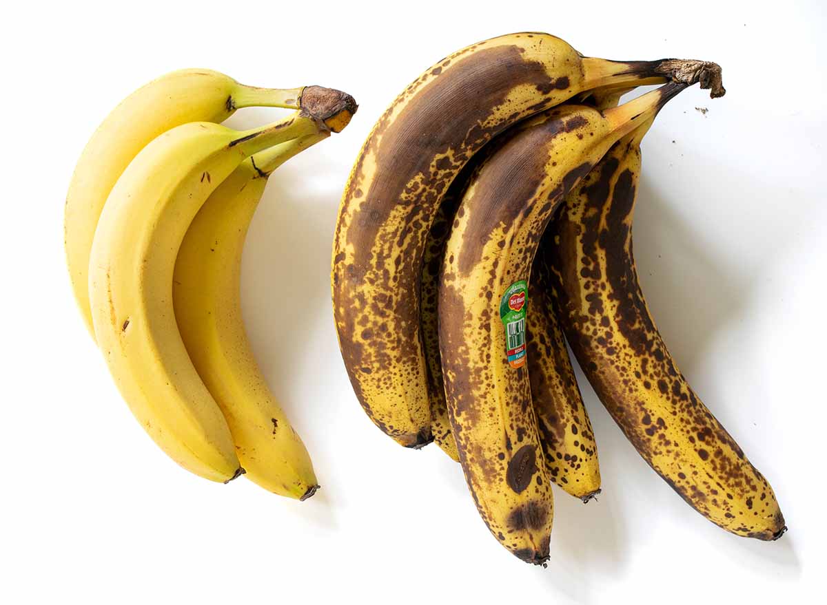 3 ripe bananas next to overripe bananas with brown and black spots. Both work great for making muffins.