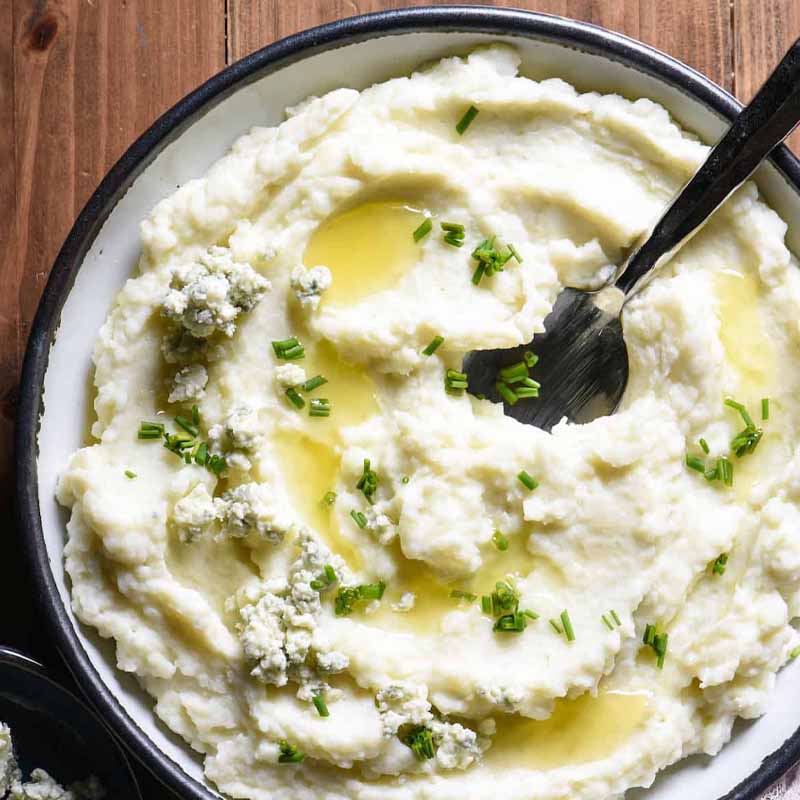 A bowl of blue cheese mashed potatoes topped with chives. Recipe by Foxes Love Lemons.