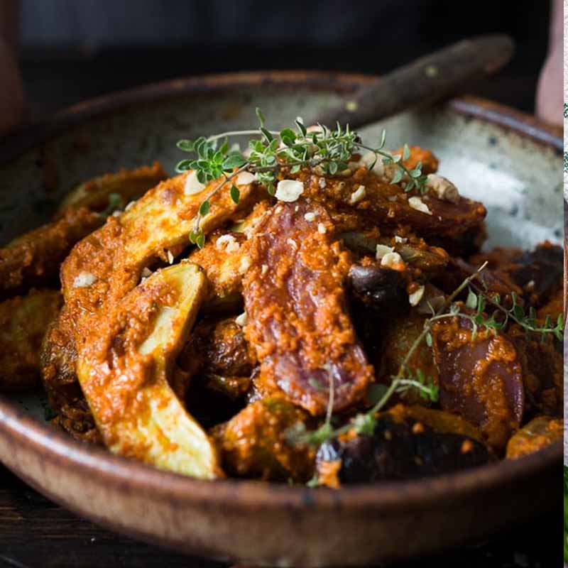 A wooden bowl of roasted potatoes covered in Romesco sauce. Recipe from Feasting At Home.