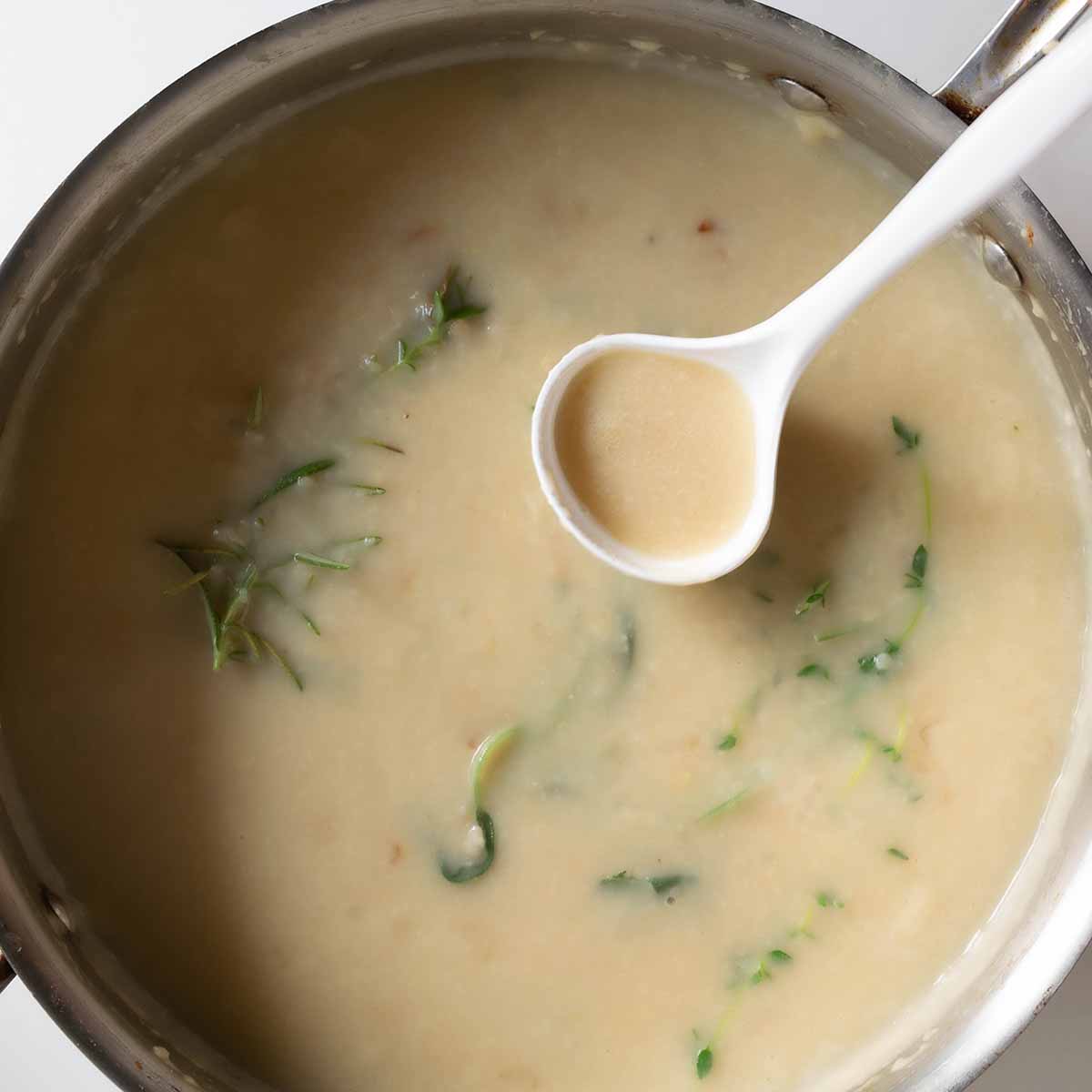 A skillet with turkey gravy for Thanksgiving made from butter and herbs, without drippings.