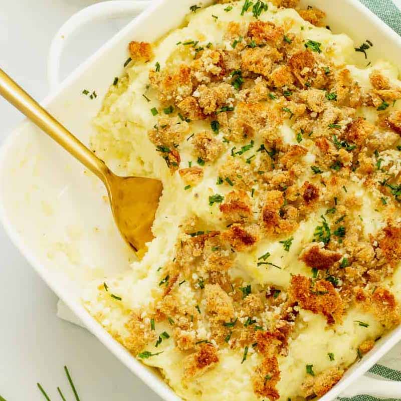Boursin mashed potatoes in a casserole dish that you can bring to Friendsgiving. Recipe by Craving Something Healthy.