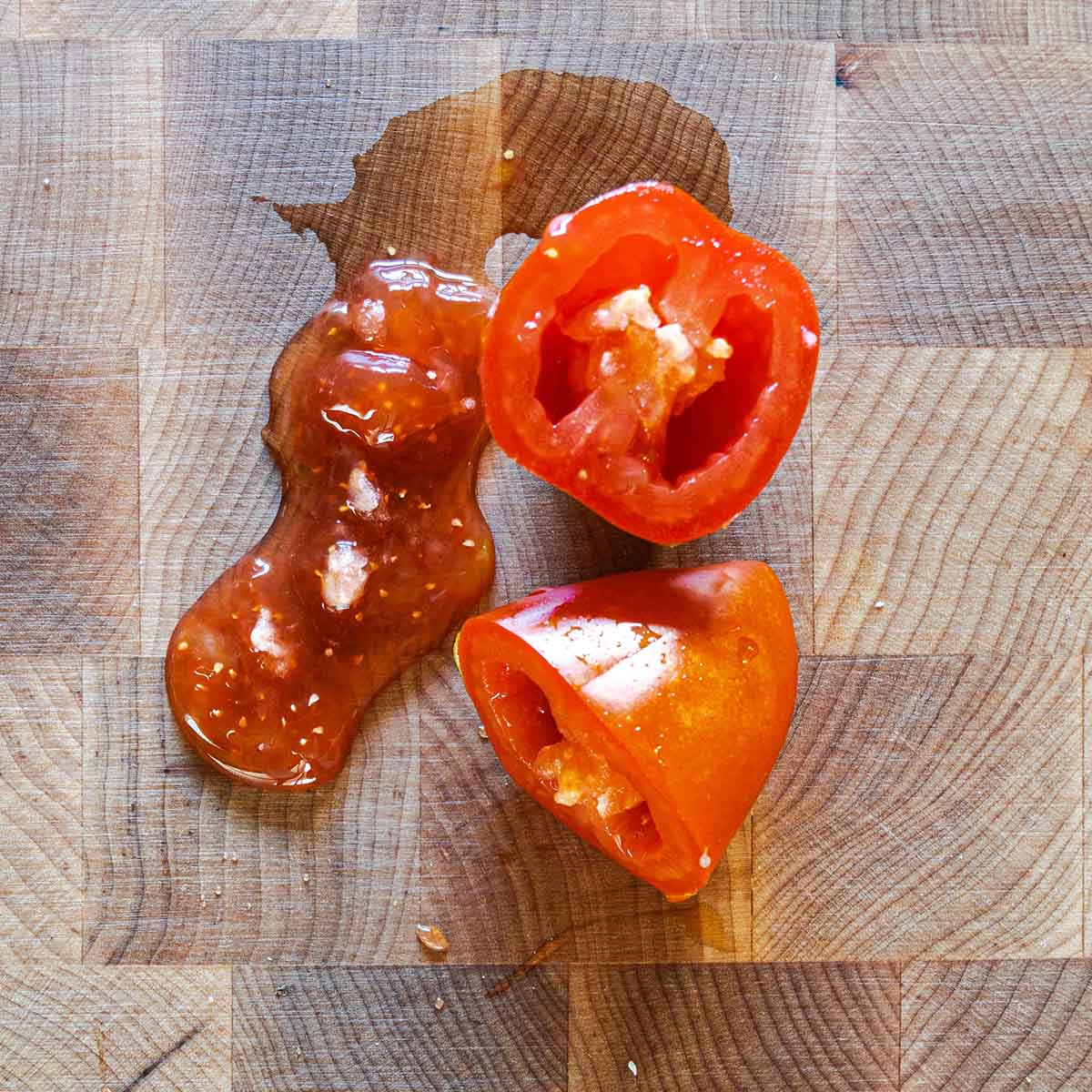 A fresh San Marzano tomato cut in half with the guts squeezed out to show the seeds and jelly.