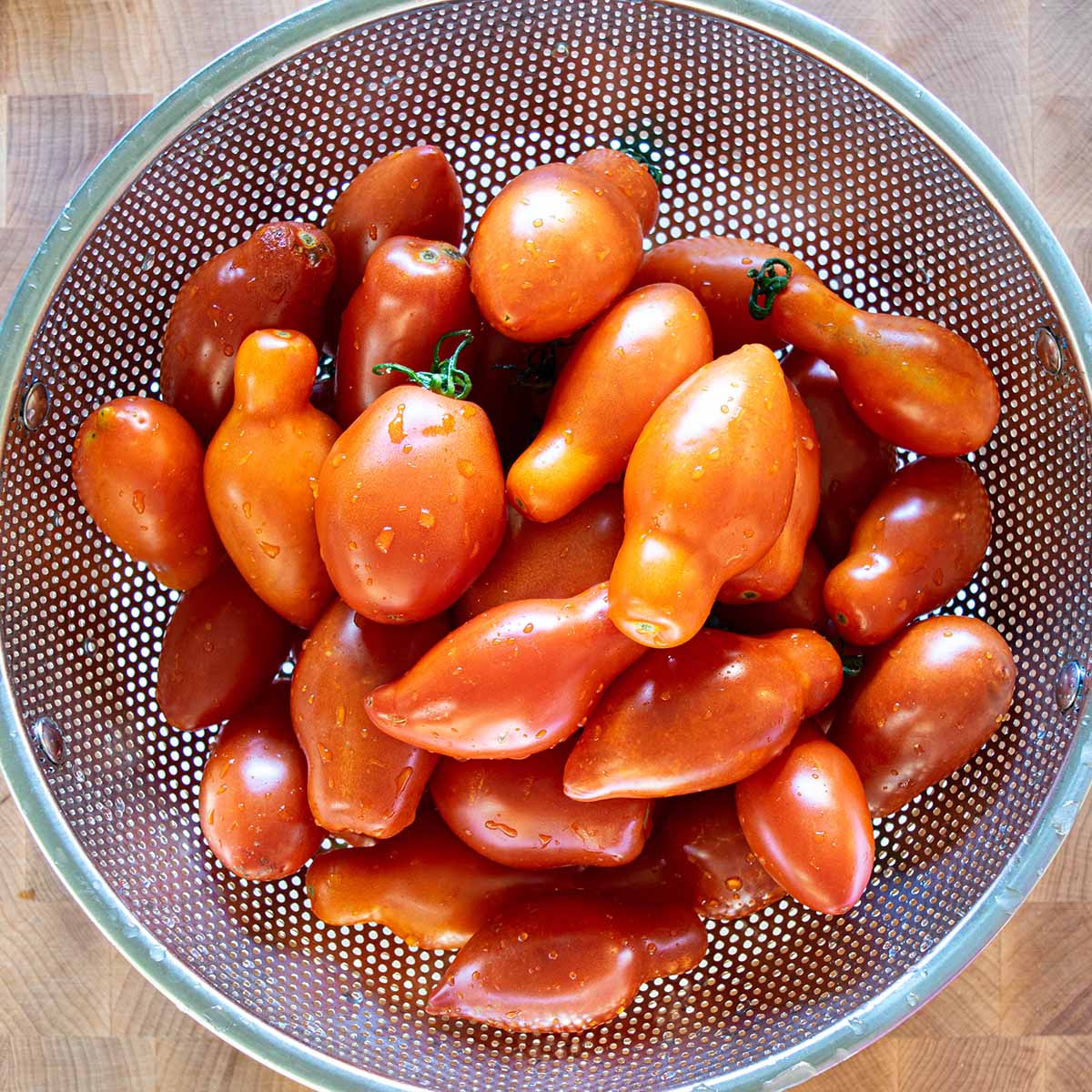 A colander filled with fresh Roma and San Marzano tomatoes