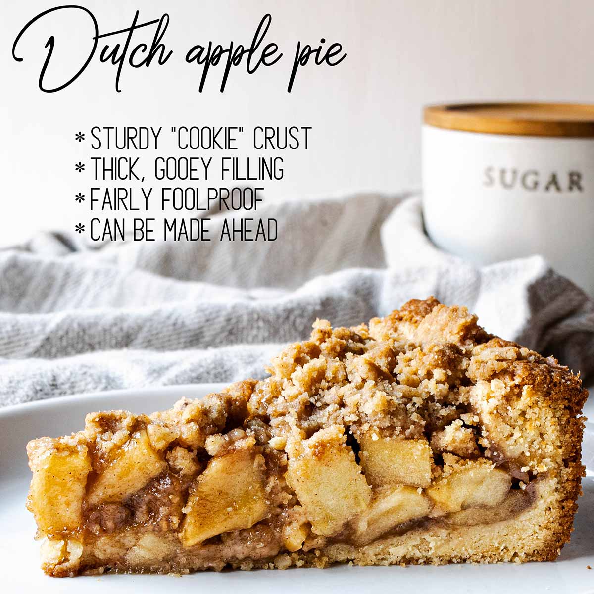 A slice of Dutch apple pie with sugar in the background and a text overlay: Sturdy "cookie" crust, thick gooey filling, foolproof, and make ahead.