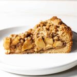 A slice of Dutch apple pie on a white plate