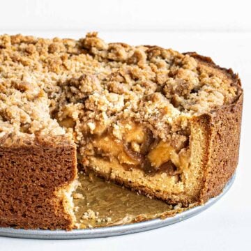 A Dutch apple pie with a slice removed to show the French cookie crust and deep dish pie.