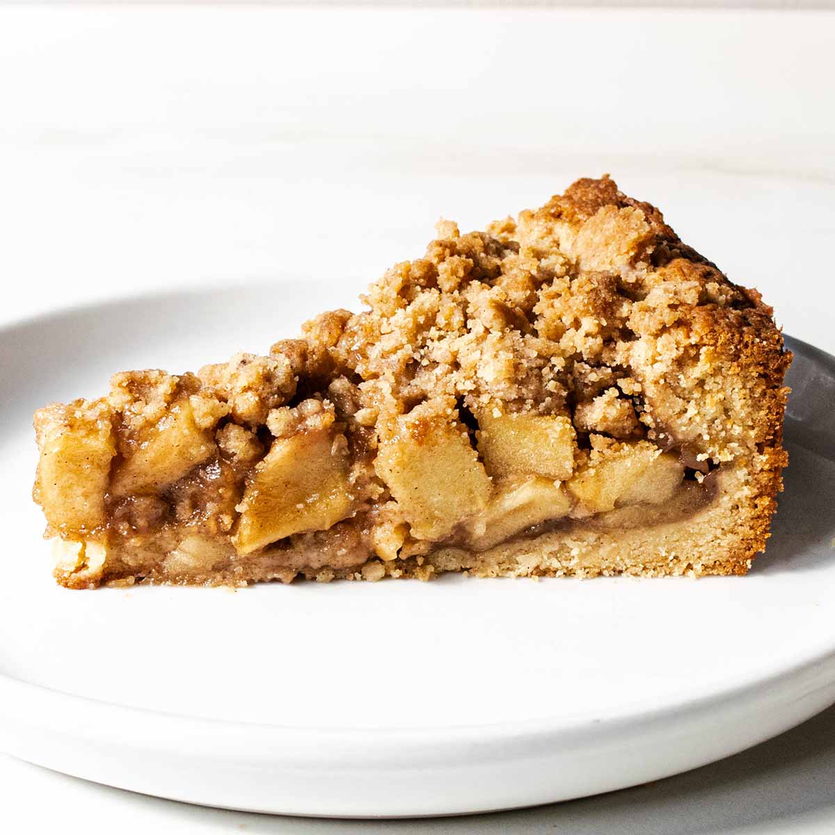 A slice of Dutch apple pie on a white plate