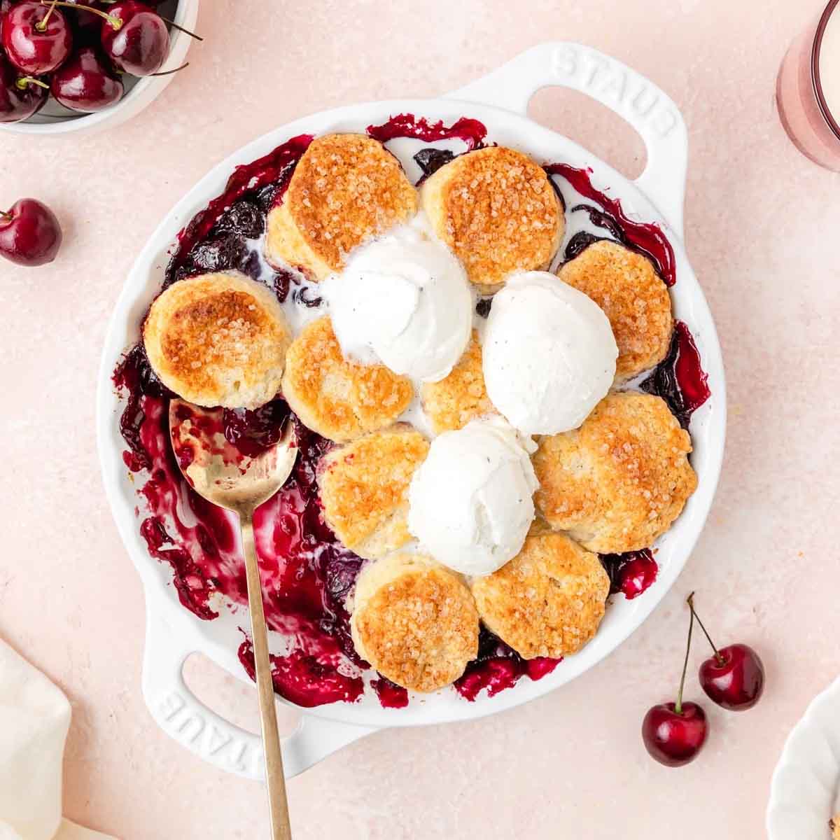 Cherry cobbler recipes: a variation that uses distinct biscuits in a white baking dish on a pink background. Recipe from Barley & Sage.