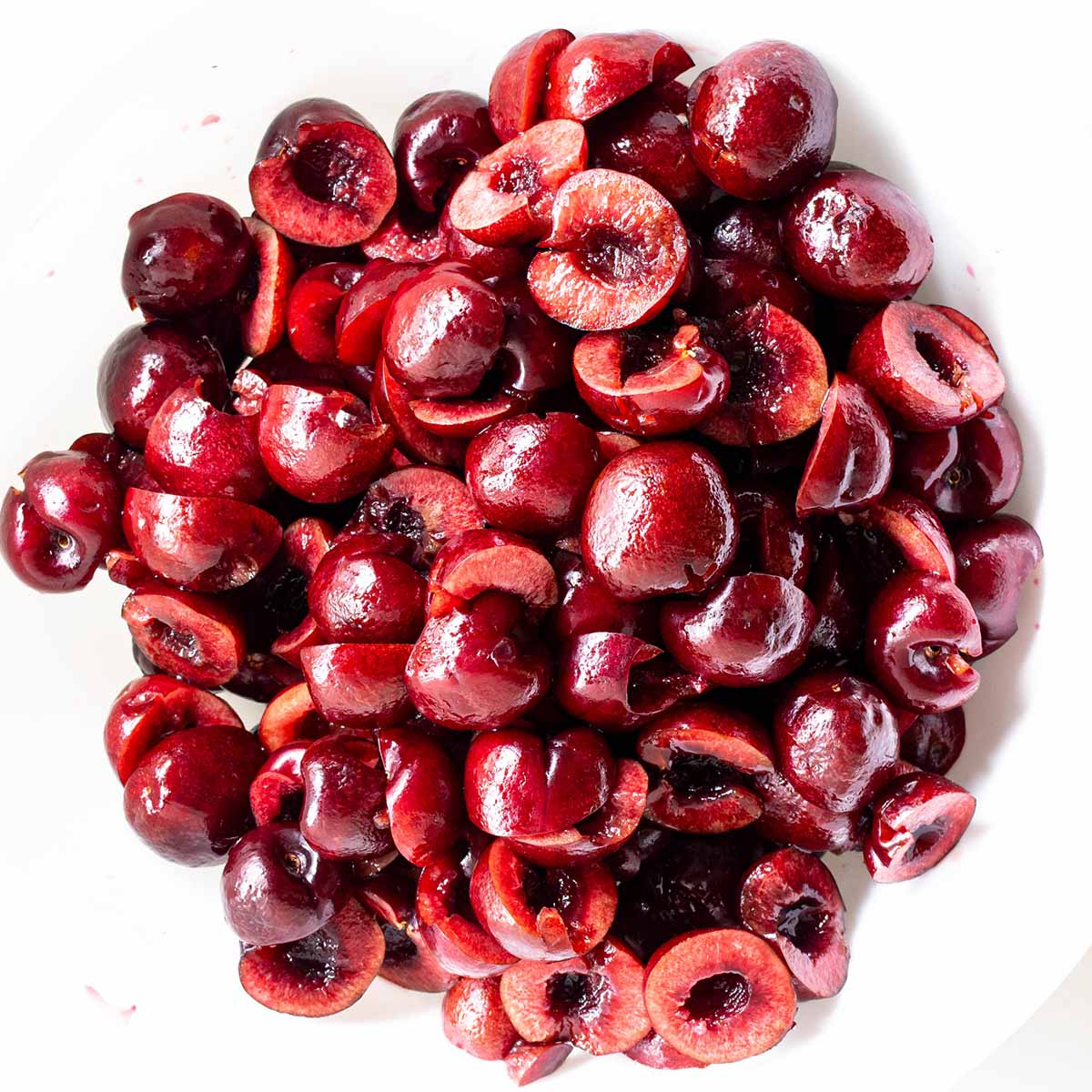 A plate of fresh cherries, pitted and halved, before being added to the cobbler.