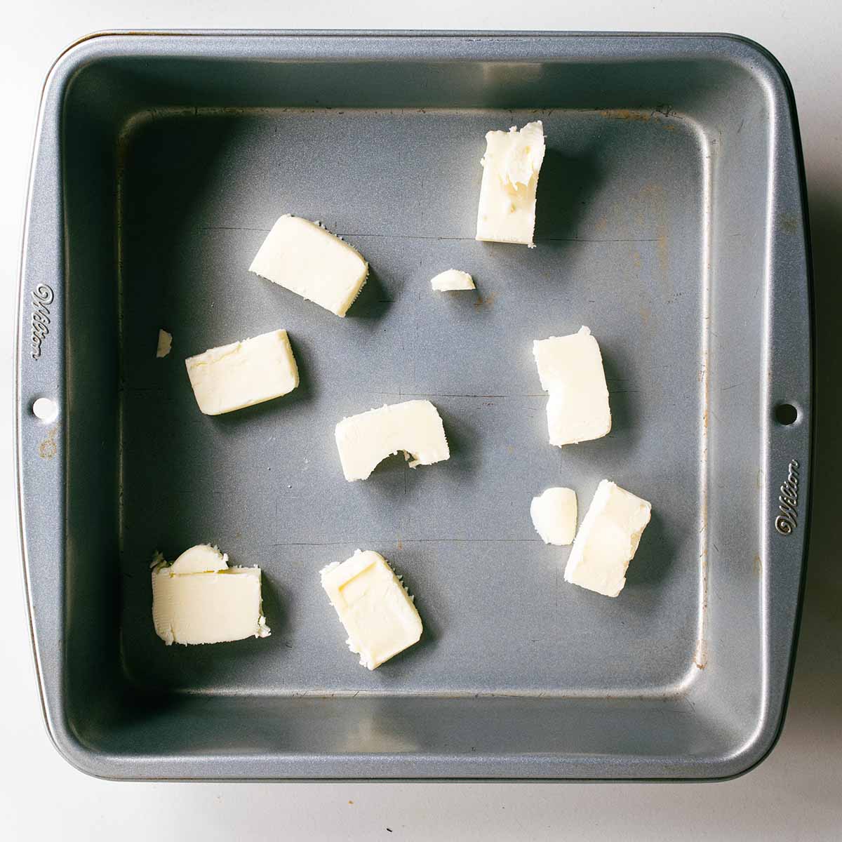 Pieces of butter in a pan, step 1 to make the cherry cobbler.