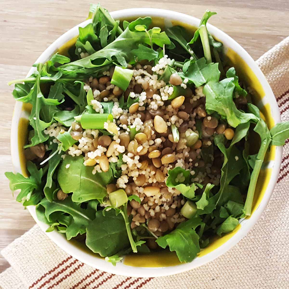 Arugula topped with couscous and lentils to add body to the salad before adding flowers