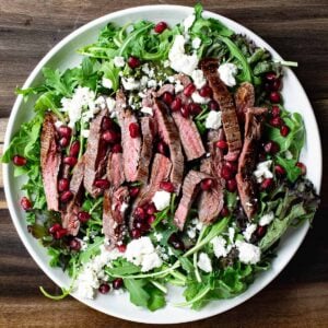 Flank steak arugula salad with pomegranate dressing and feta cheese.