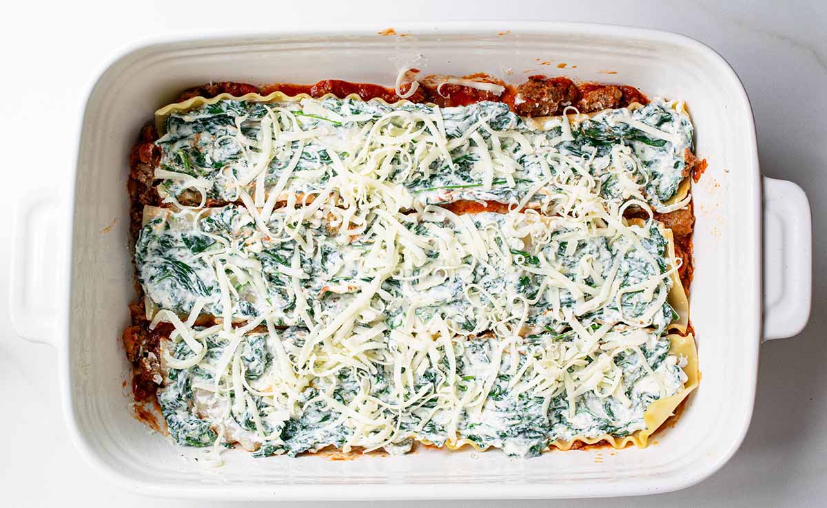 Add shredded mozzarella as the next layer on top of the ricotta mixture.