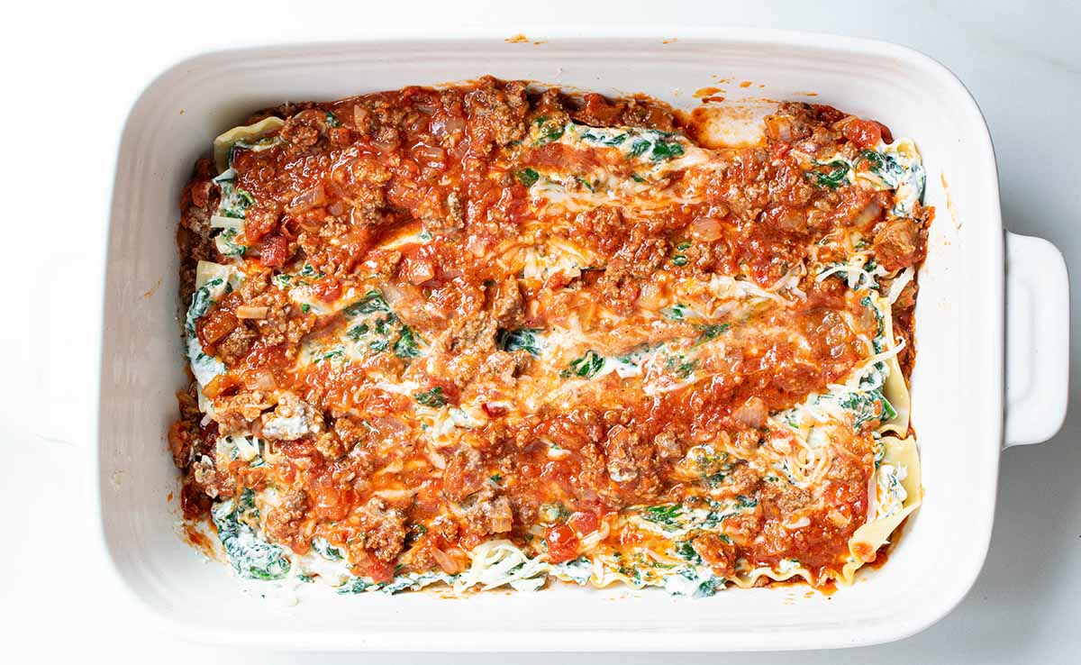 Sauce is added as the last layer before the next set of noodles.
