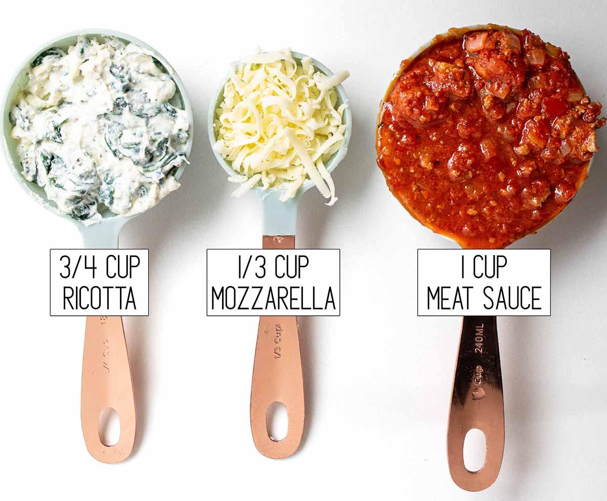 Measuring cups with ingredients to show how much to use for each layer: ¾ cup ricotta filling, ⅓ cup shredded mozzarella, and 1 cup of homemade meat sauce.