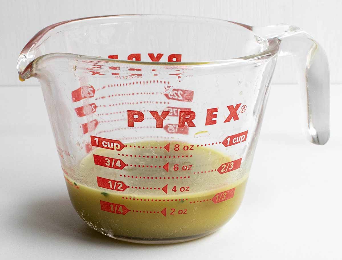 A glass measuring cup with 3 ounces of water squeezed from the cooked spinach to prevent a watery lasagna.